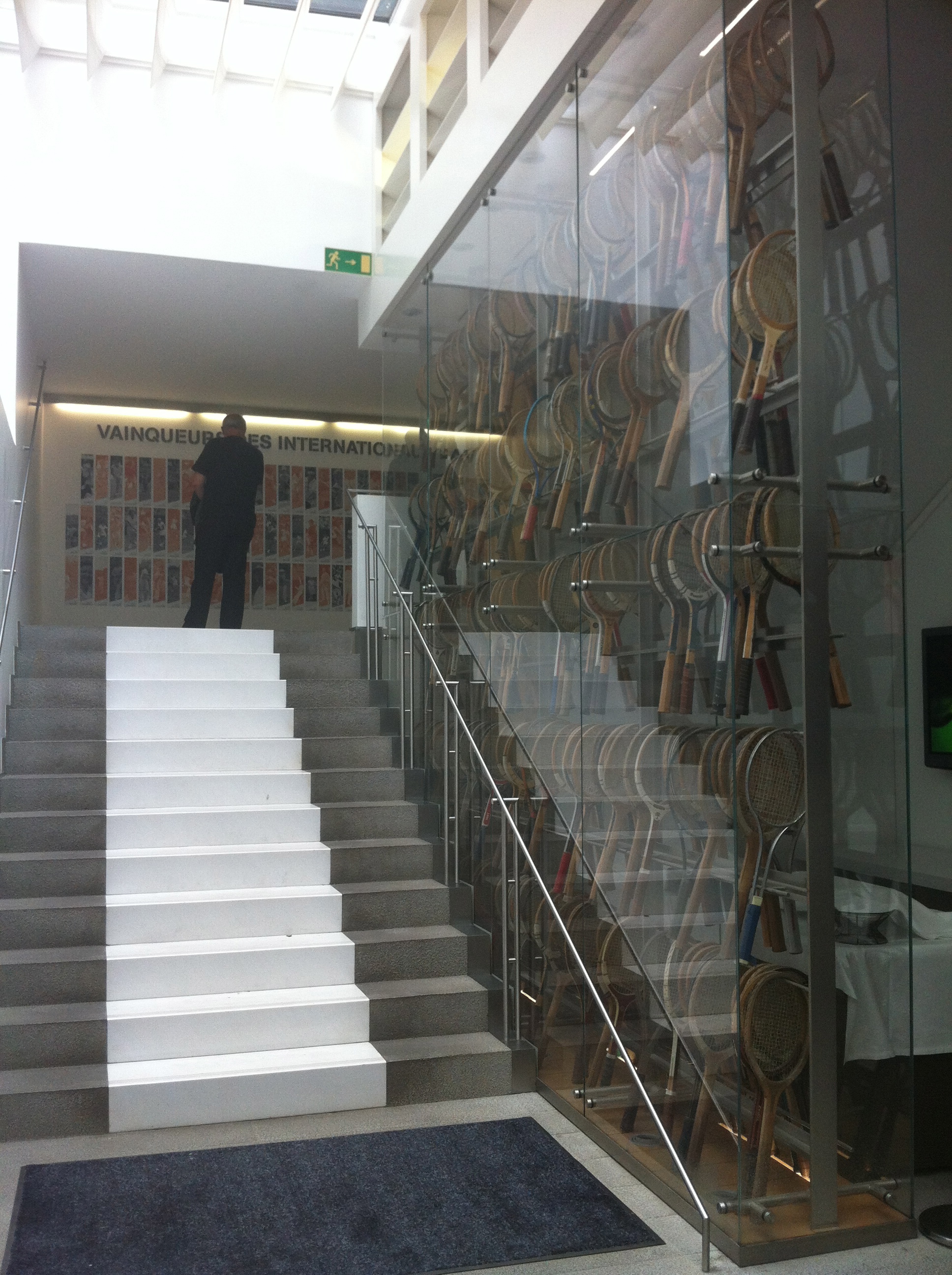 À droite, une vitrine de raquettes ; en haut, une mosaïque de photos réunissant tous les champions couronnés à Roland Garros.